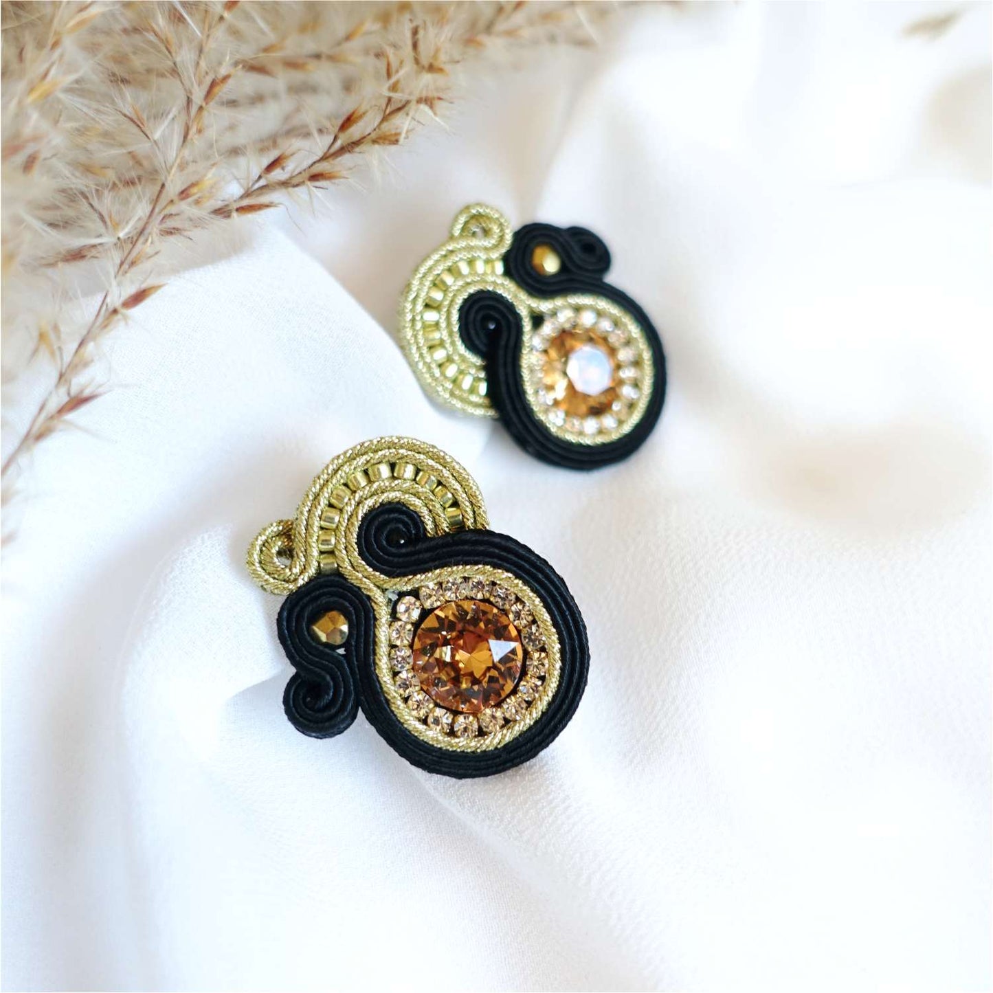 Small black and gold soutache earrings on the ear, 169 Aurora