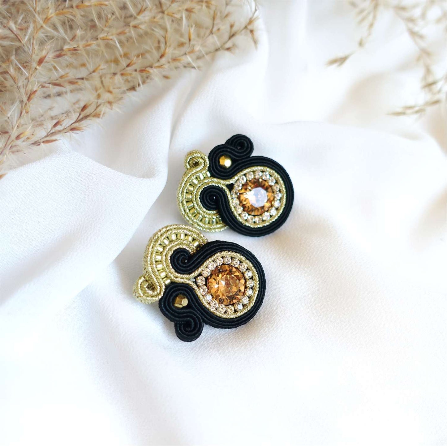Small black and gold soutache earrings on the ear, 169 Aurora