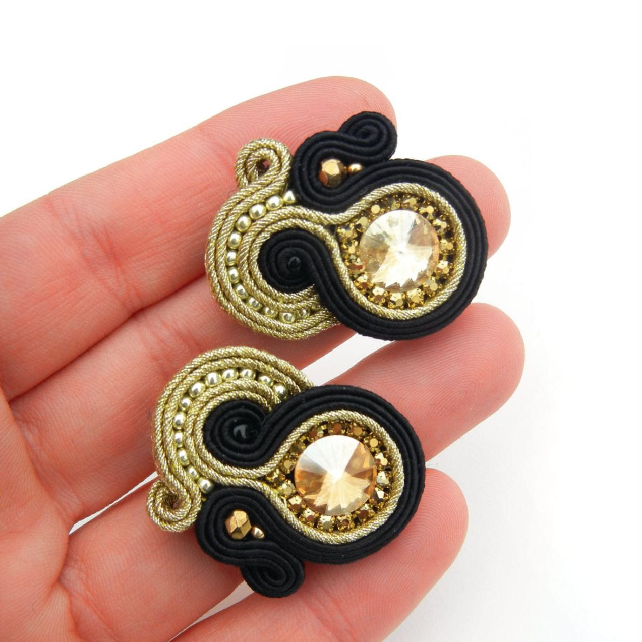 Small black and gold soutache earrings on the ear, 169 Aurora